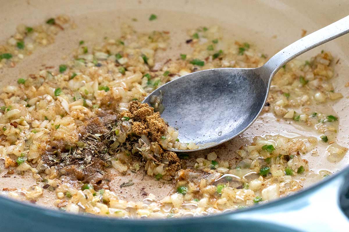 Small pieces of onion and spices sauteing in a pan.