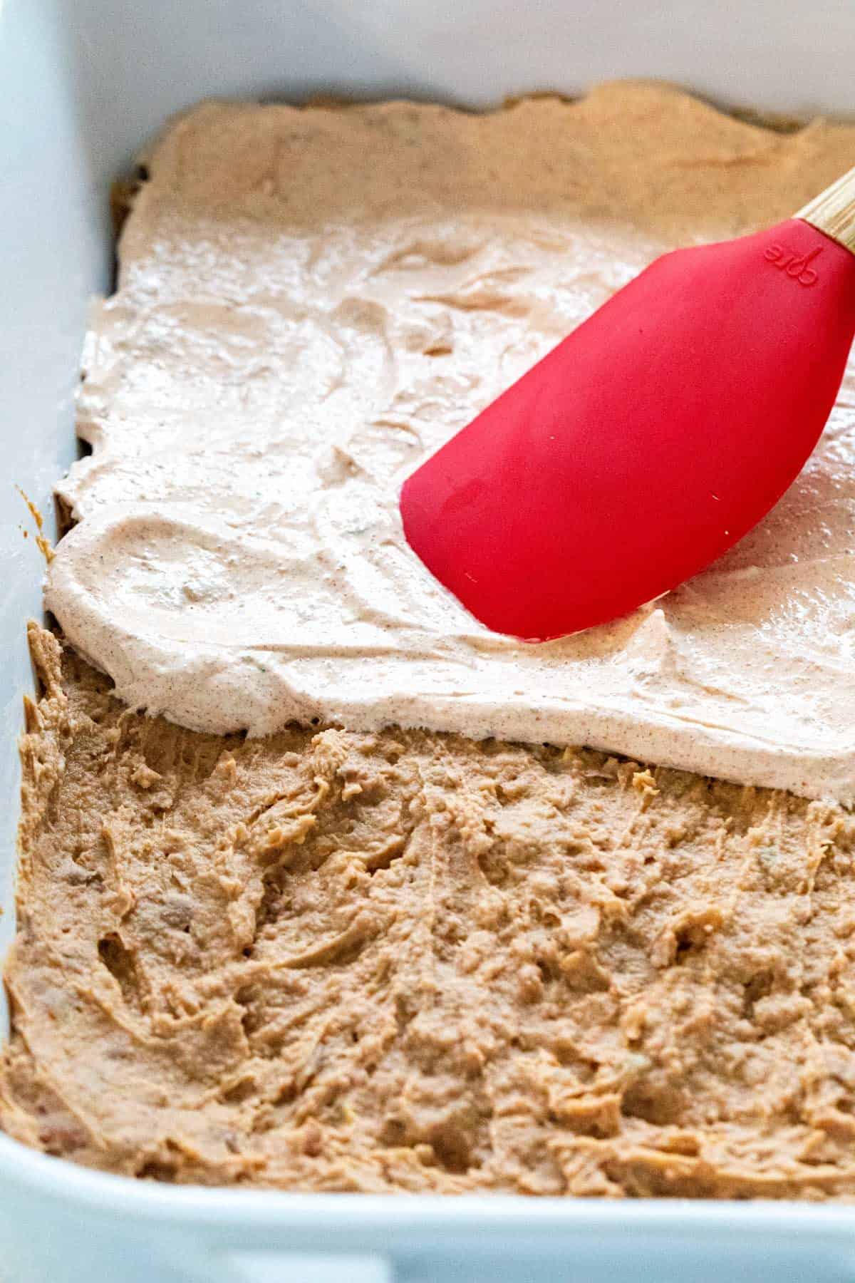 spreading sour cream over refried beans