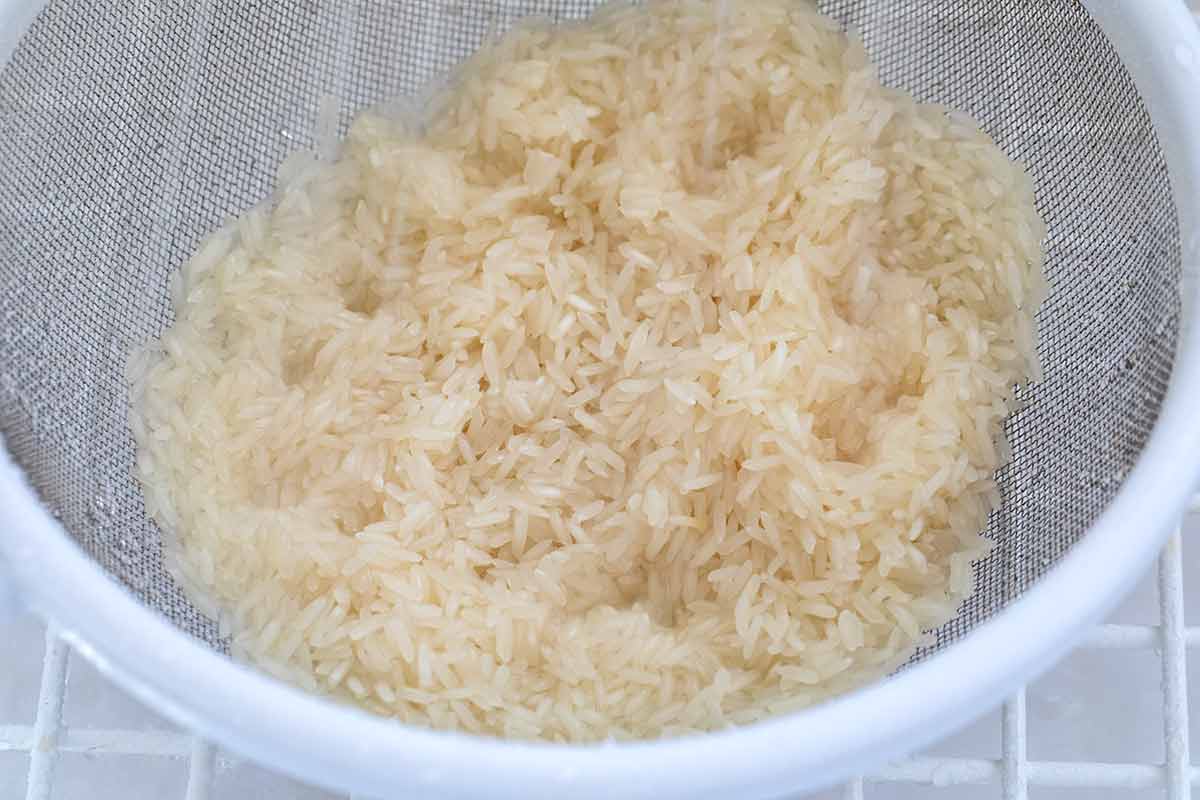 Uncooked white rice in a fine mesh strainer