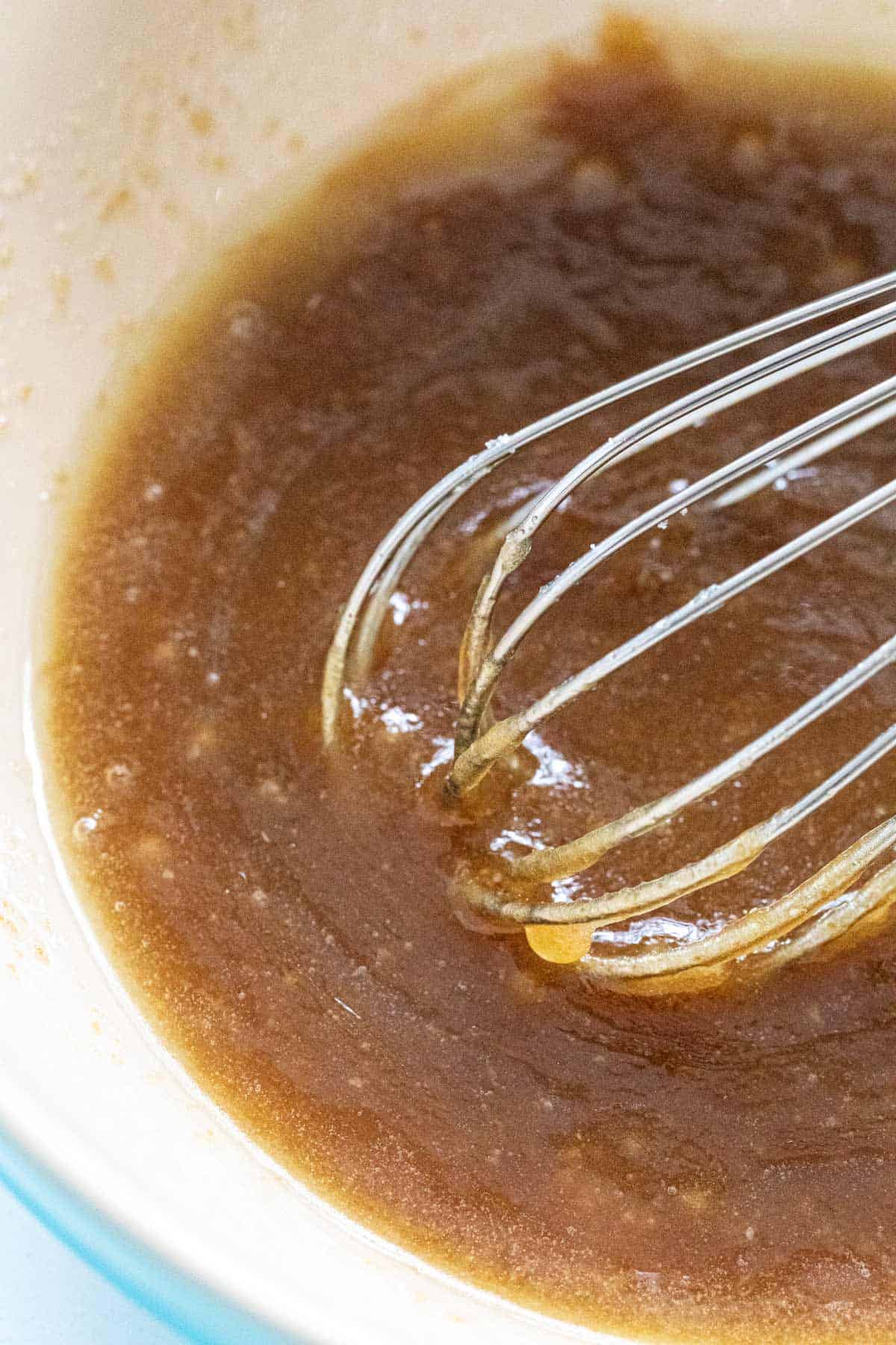 Whisking a homemade caramel sauce in a bowl.