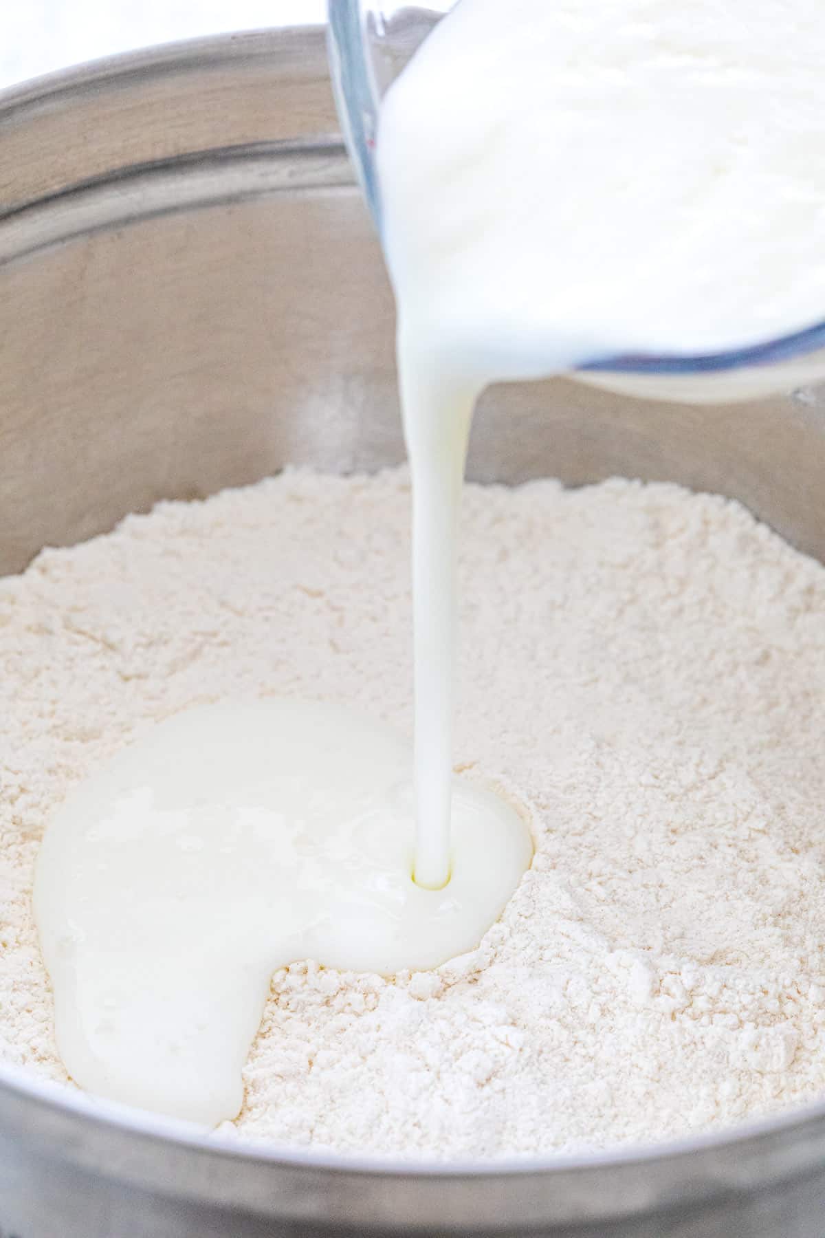 Buttermilk being poured into a mixing bowl of flour.