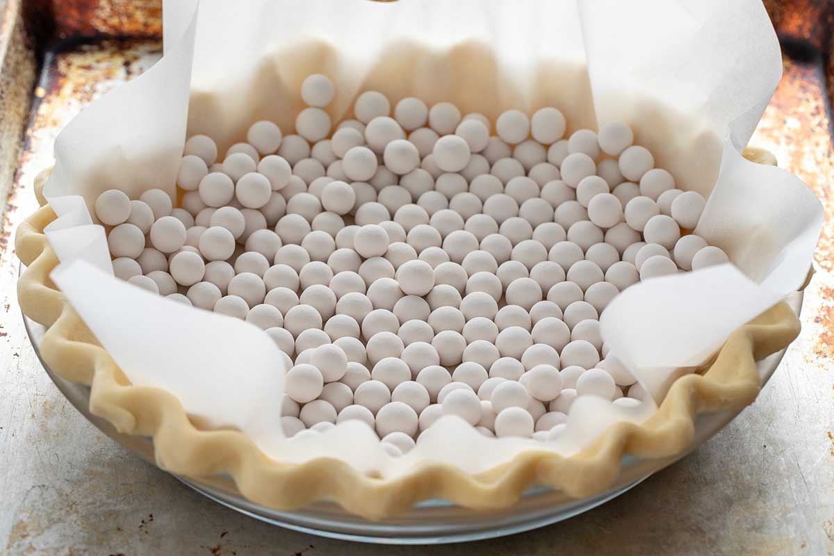 Ceramic pie weights inside a paper-lined pie crust.