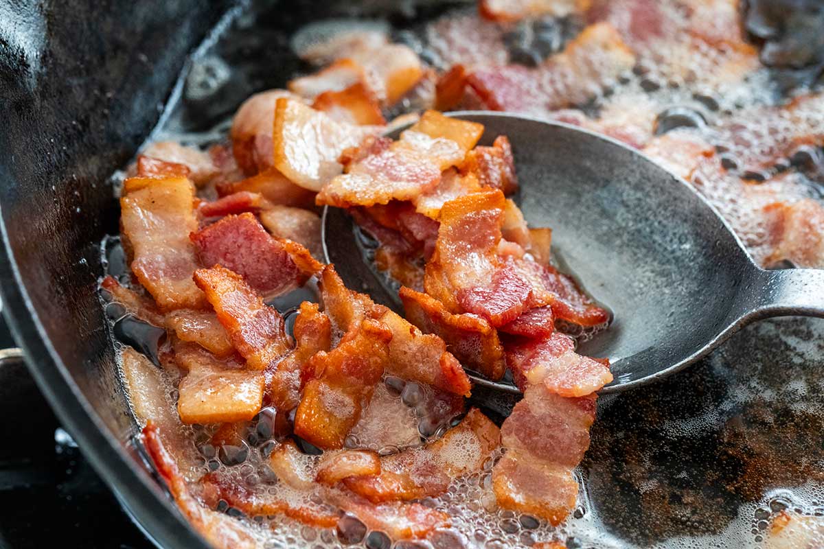 Sautéing chopped bacon in a cast iron skillet.