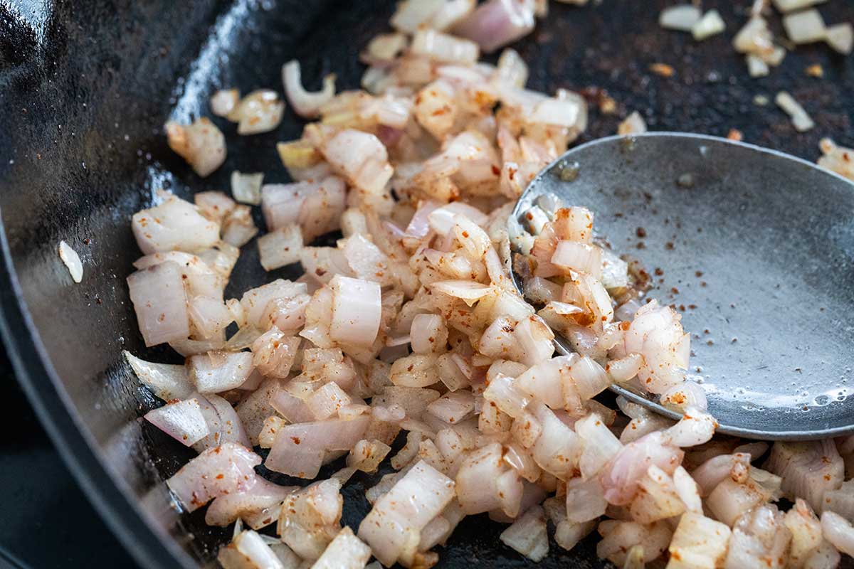 Diced shallots sauteing in a pan.