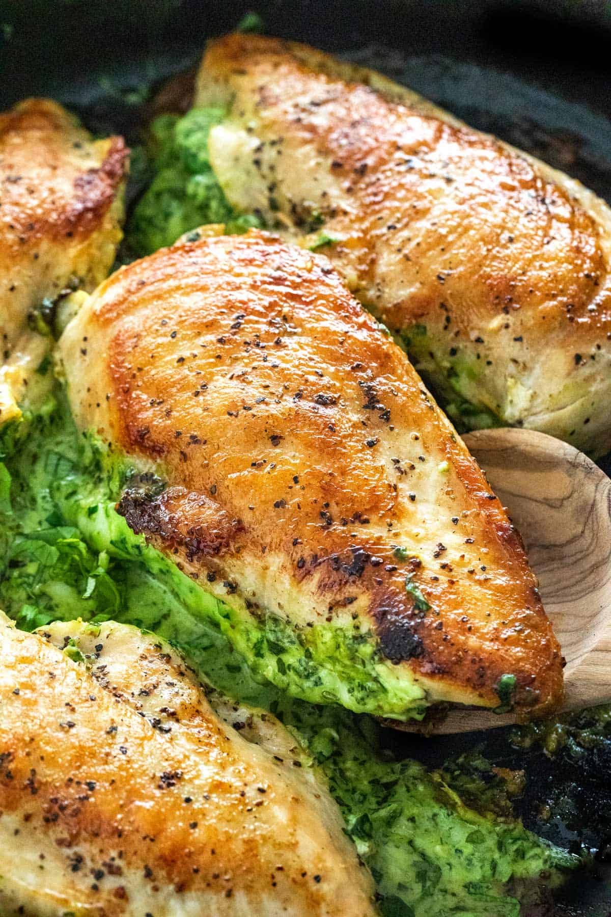 Chicken breast with spinach stuffing oozing out into the pan.