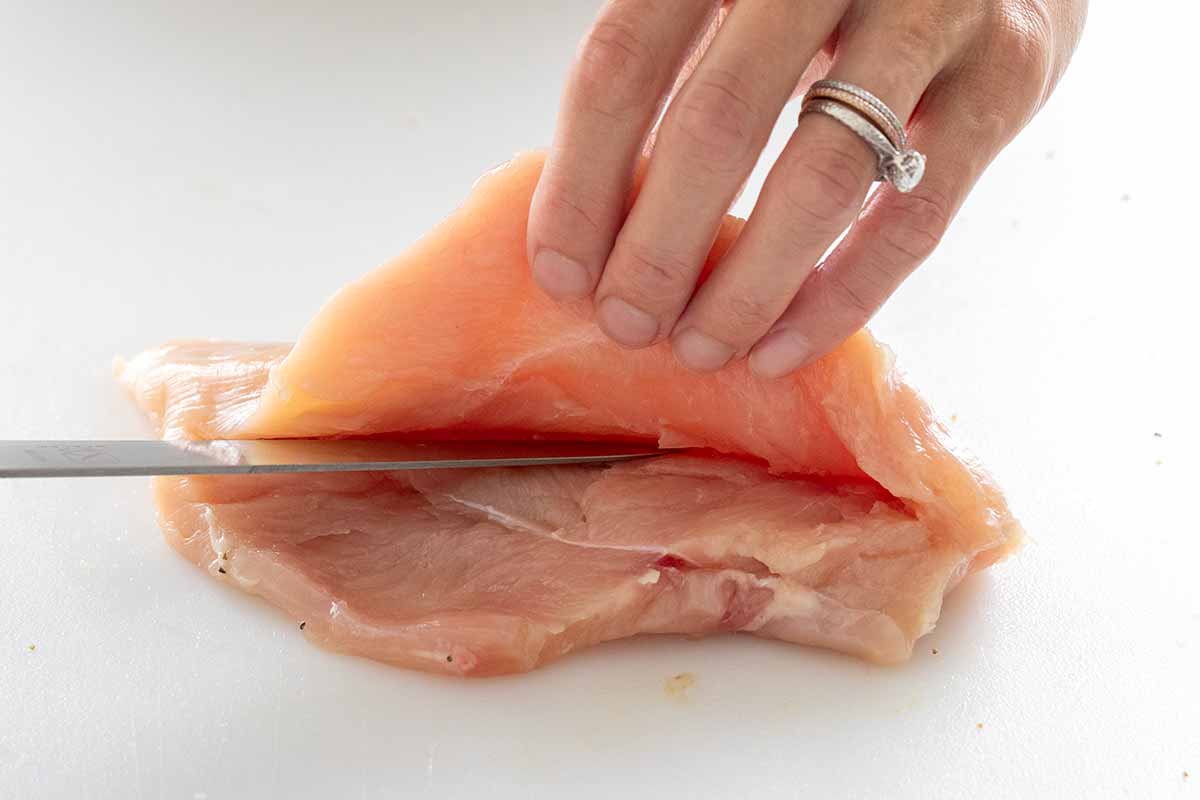 Cutting a pocket into the side of a chicken breast.