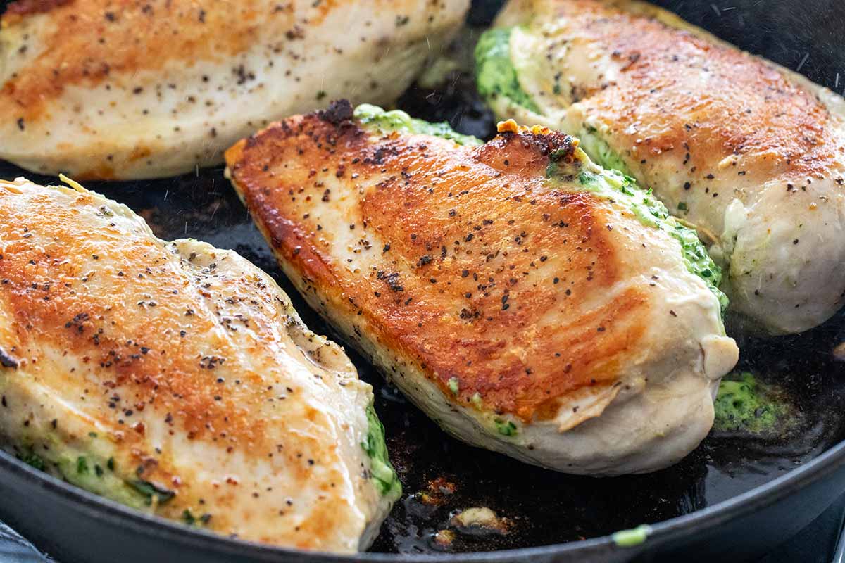 Searing the surface of a chicken breast in a pan.