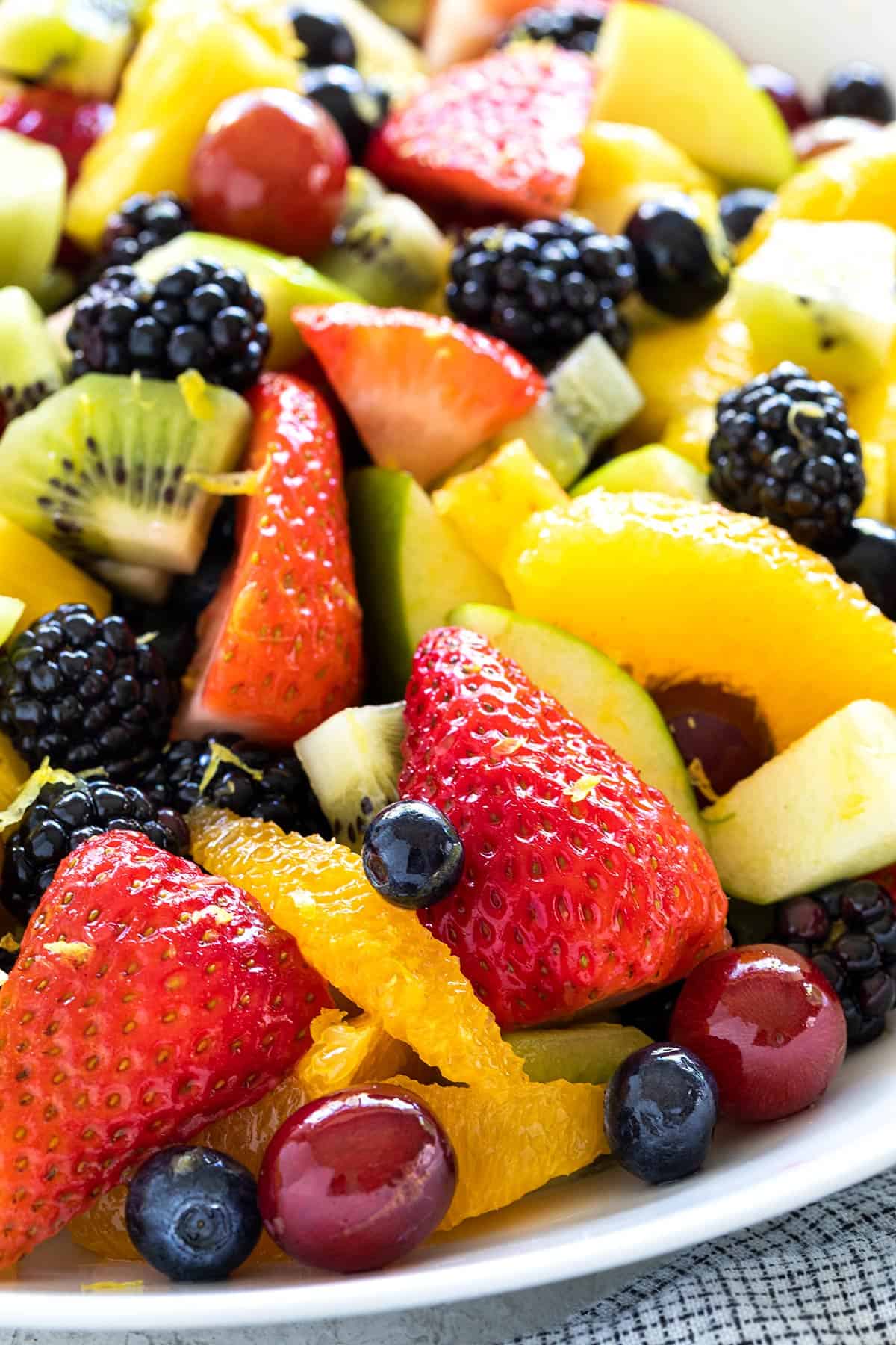 Close up of a sliced strawberries, blueberries, grapes, and orange slices.