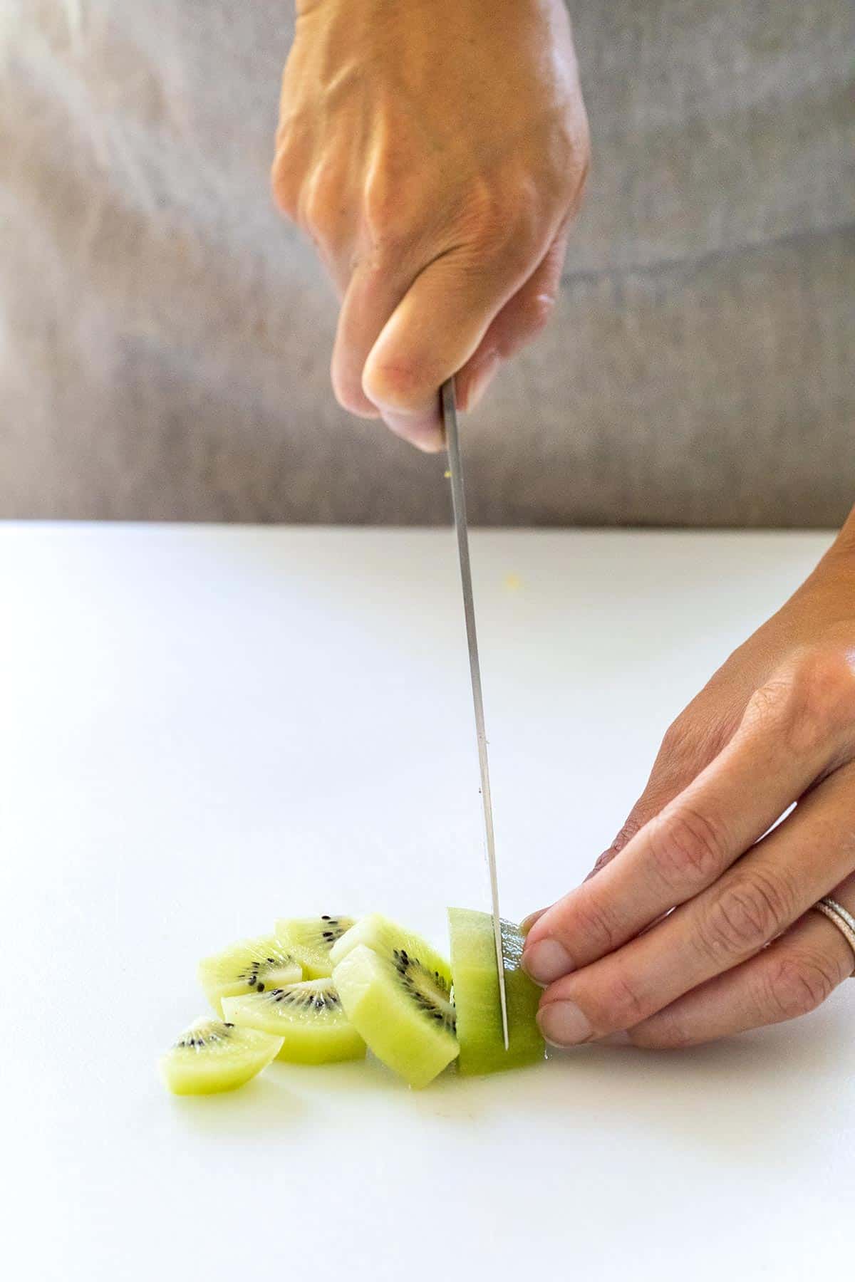 Slicing kiwi on a cutting board.