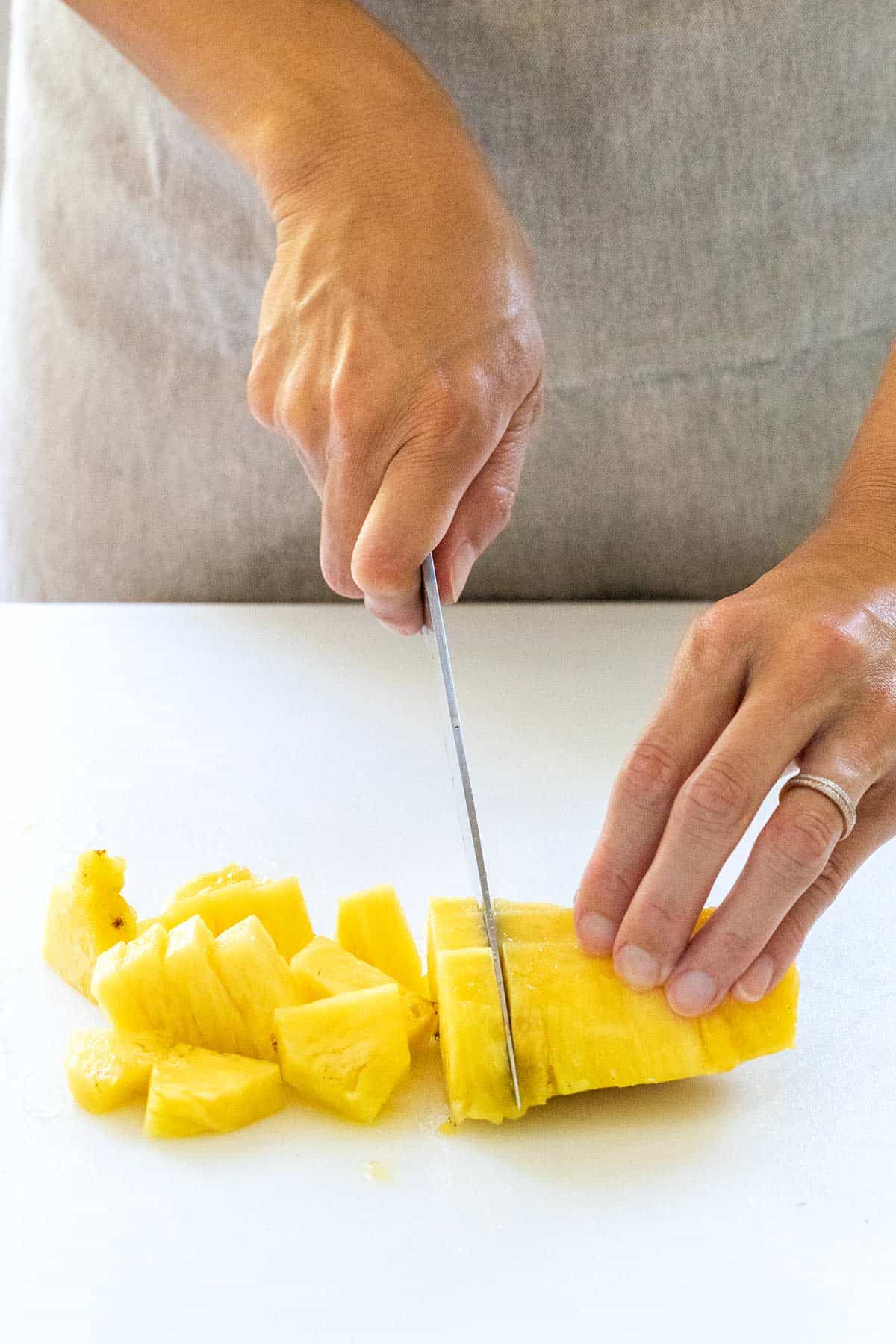 Cutting pineapple into smaller slices.