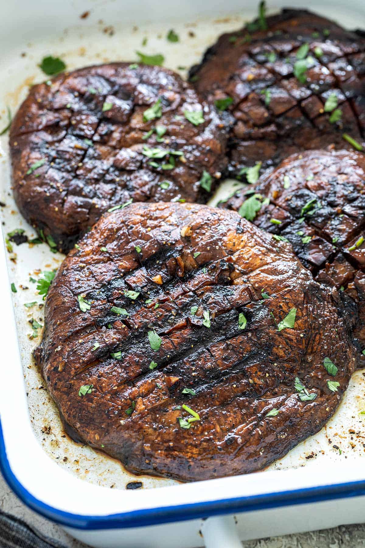 Four grilled mushrooms in a baking dish.
