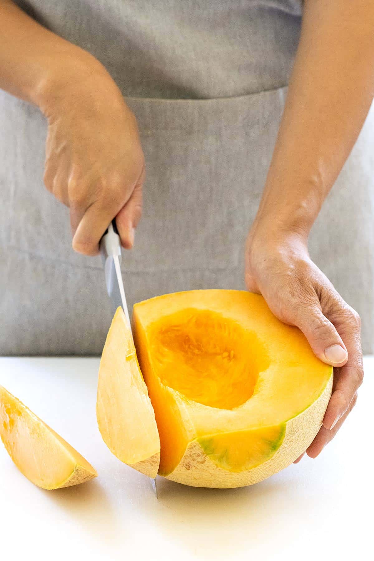 Cutting wedges into a melon with the rind on.