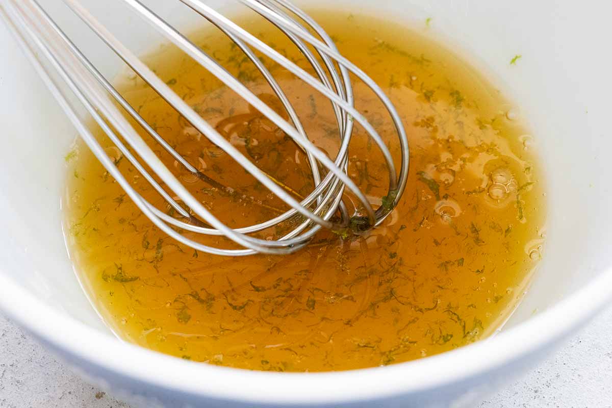 Whisking mixing a bowl of honey and lime salad dressing.