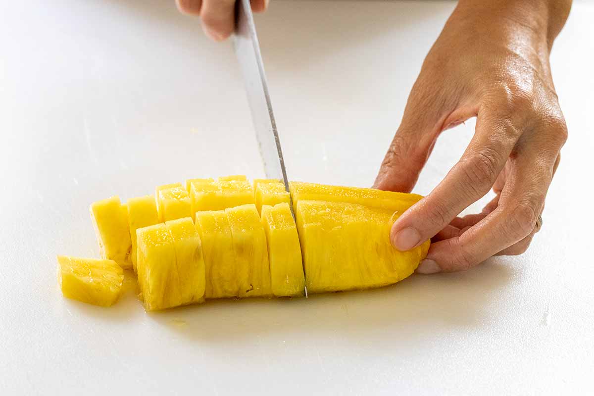 Person cutting a pineapple into chunks.