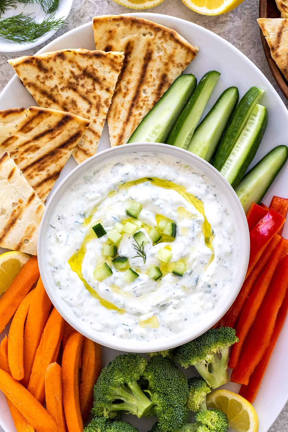 Platter of vegetables, pita, and a bowl of tzatziki sauce.