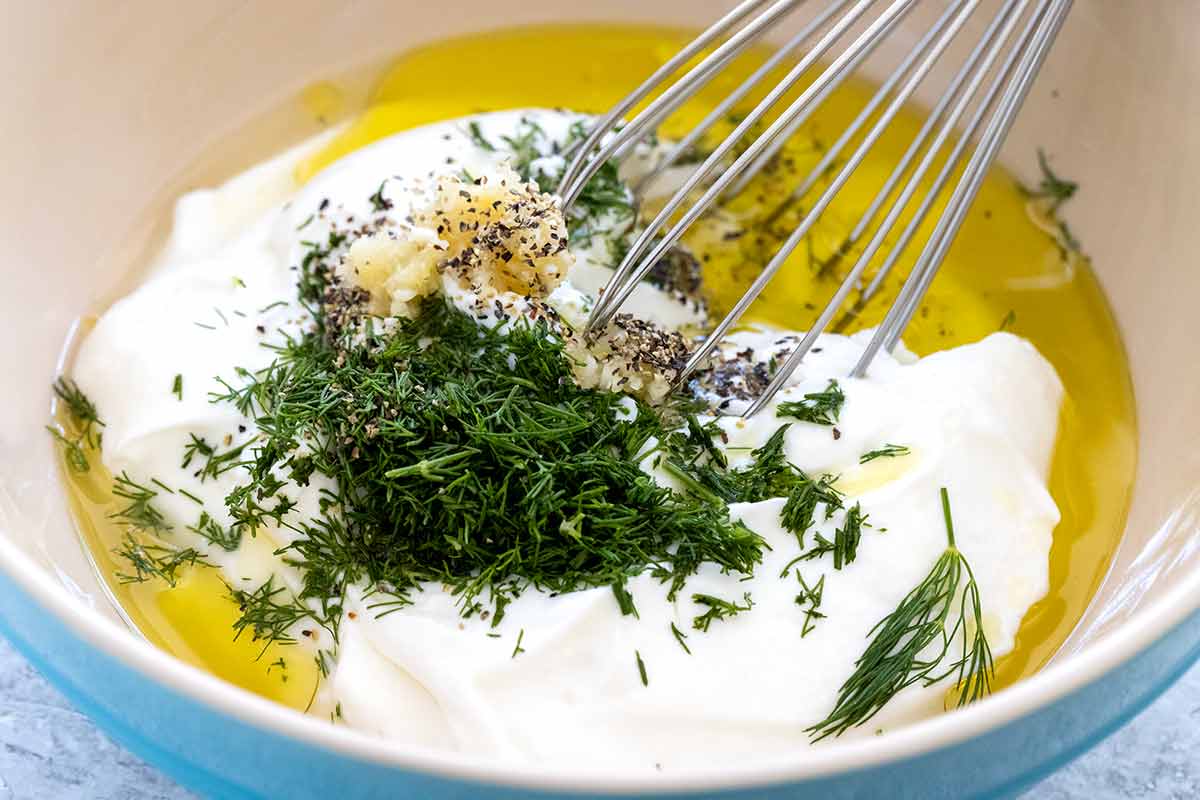 Yogurt, dill, oil, and seasonings in a mixing bowl.