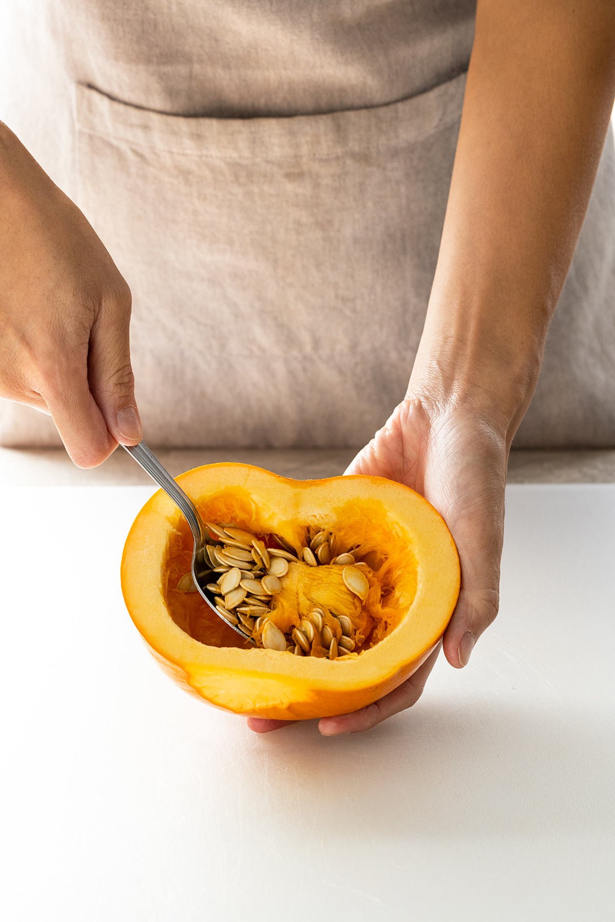 Jessica scooping the seeds out of a pumpkin.