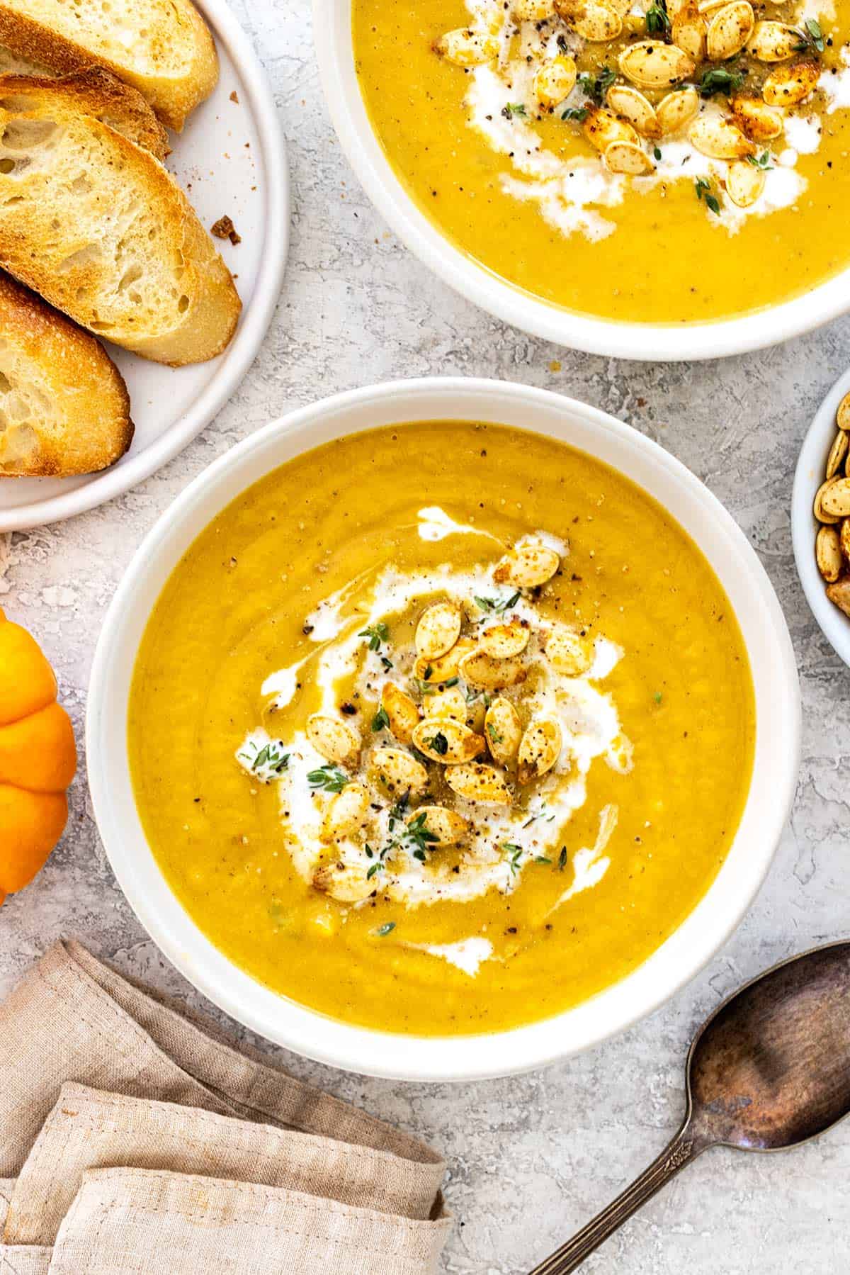 Orange colored soup with pumpkin seeds on top.