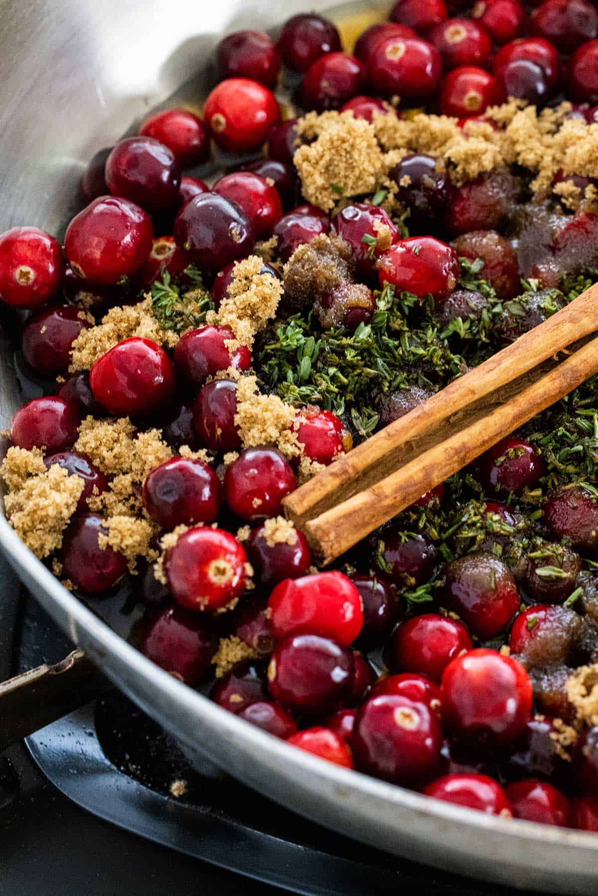 Cranberries and herbs cooking in a pan.