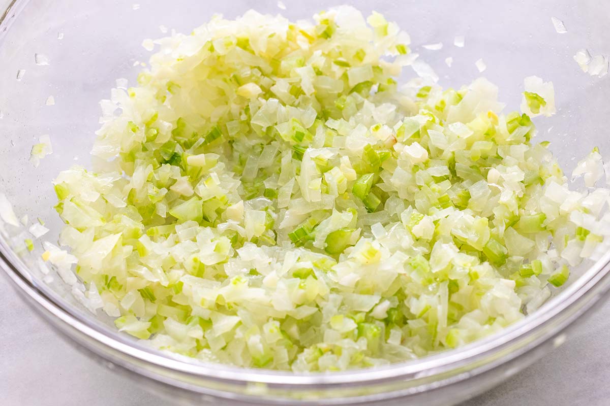Finely chopped onions and celery in a clear glass bowl.