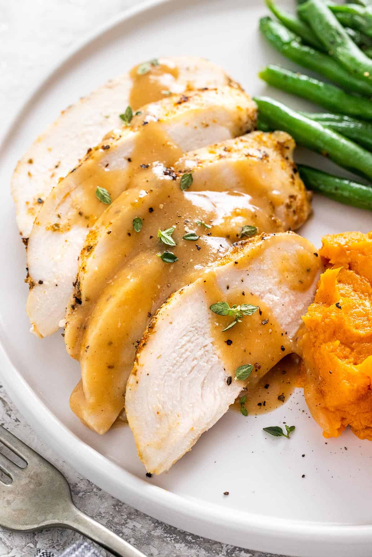 Sliced chicken breasts with gravy on top.