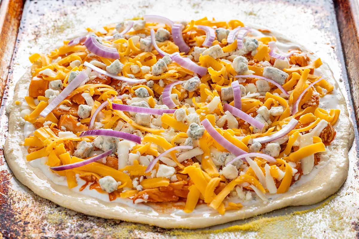 Ranch, shredded buffalo chicken, cheddar, and mozzarella on a pizza dough.
