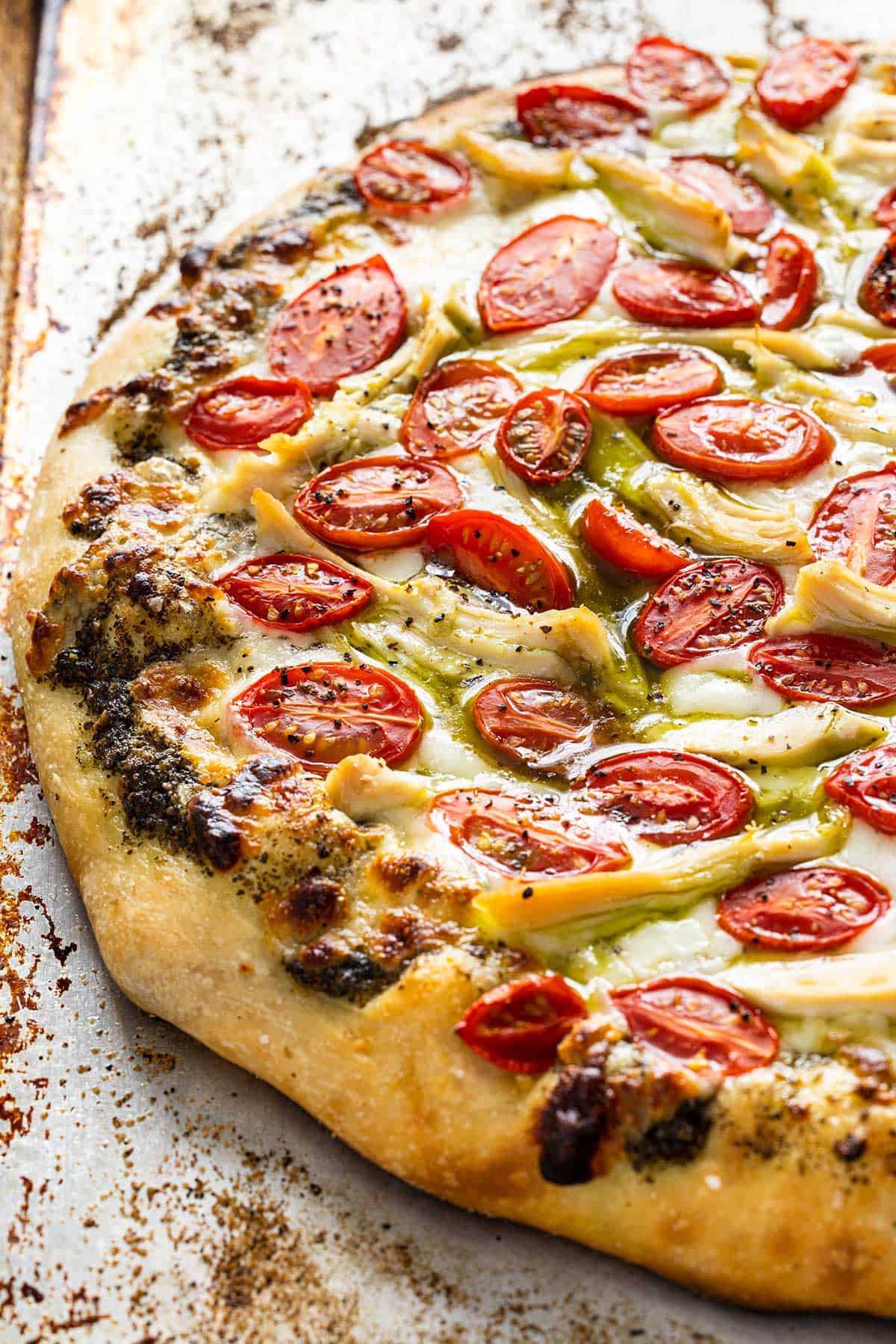 Chicken pesto pizza on a baking sheet hot out the oven.