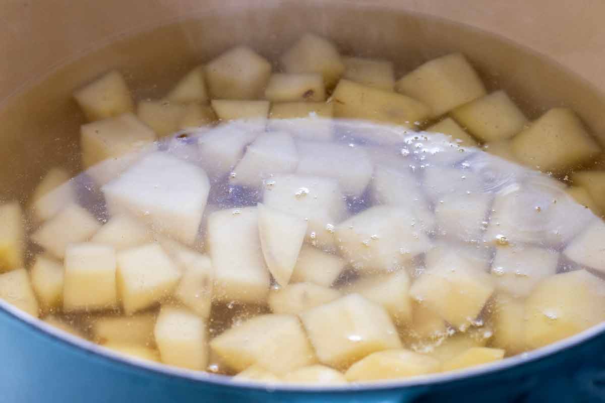 Cubes of potatoes cooking in a pot of hot water.