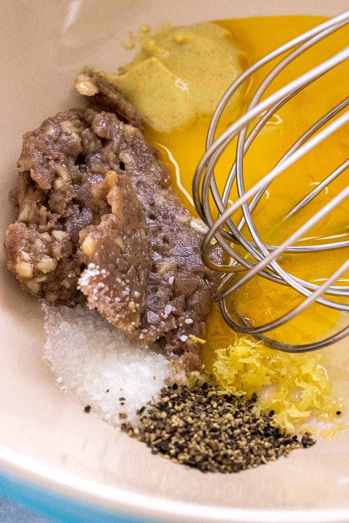 Caesar dressing ingredients placed in a mixing bowl.