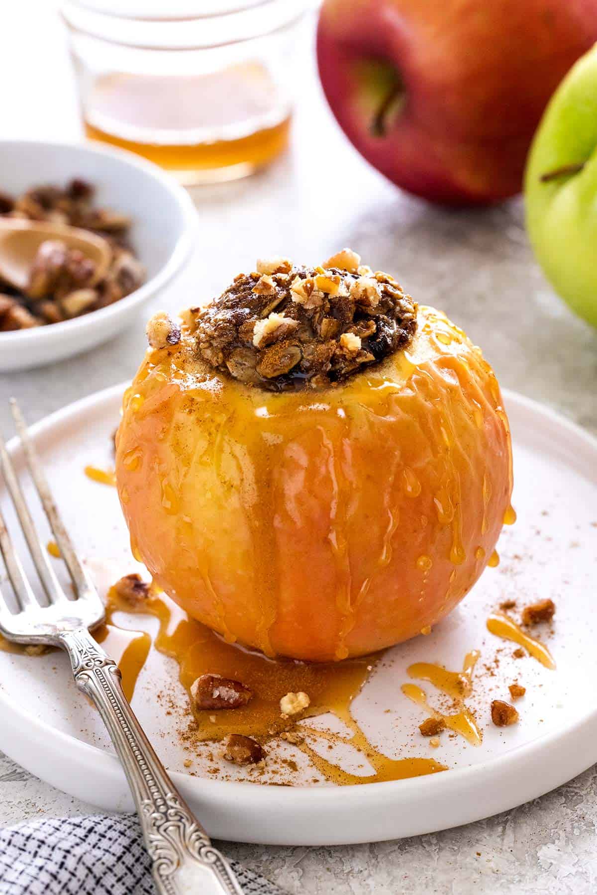 Baked apple on a white plate with caramel sauce drizzled on top.