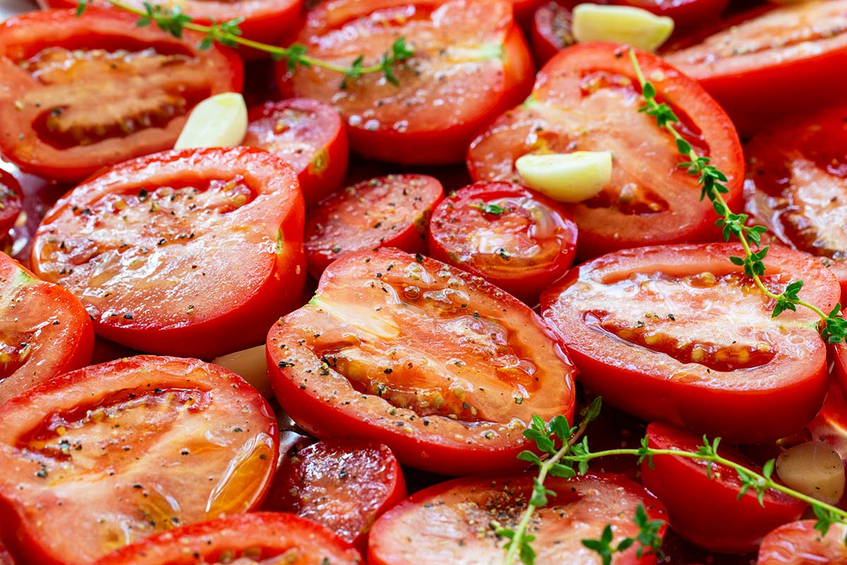 Slices tomatoes with olive and cracked pepper on top.
