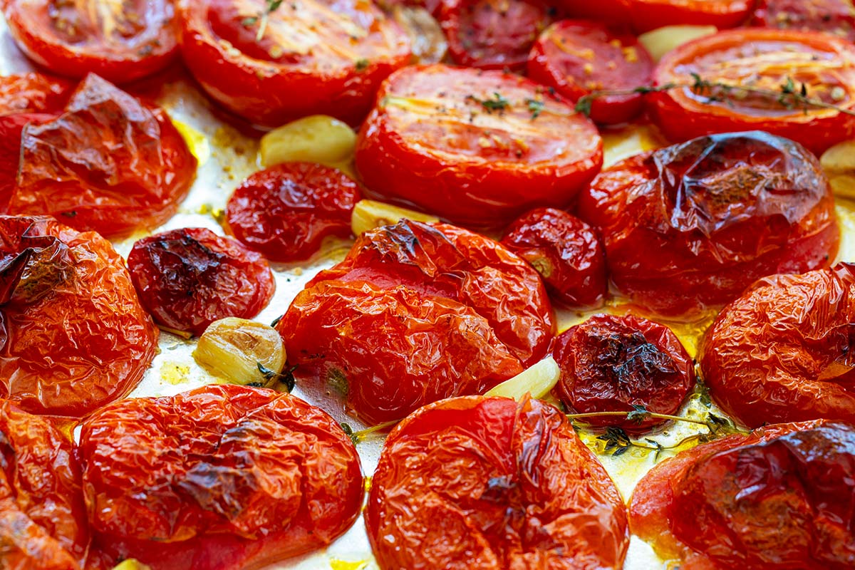 Roasted tomatoes and garlic on a baking sheet.