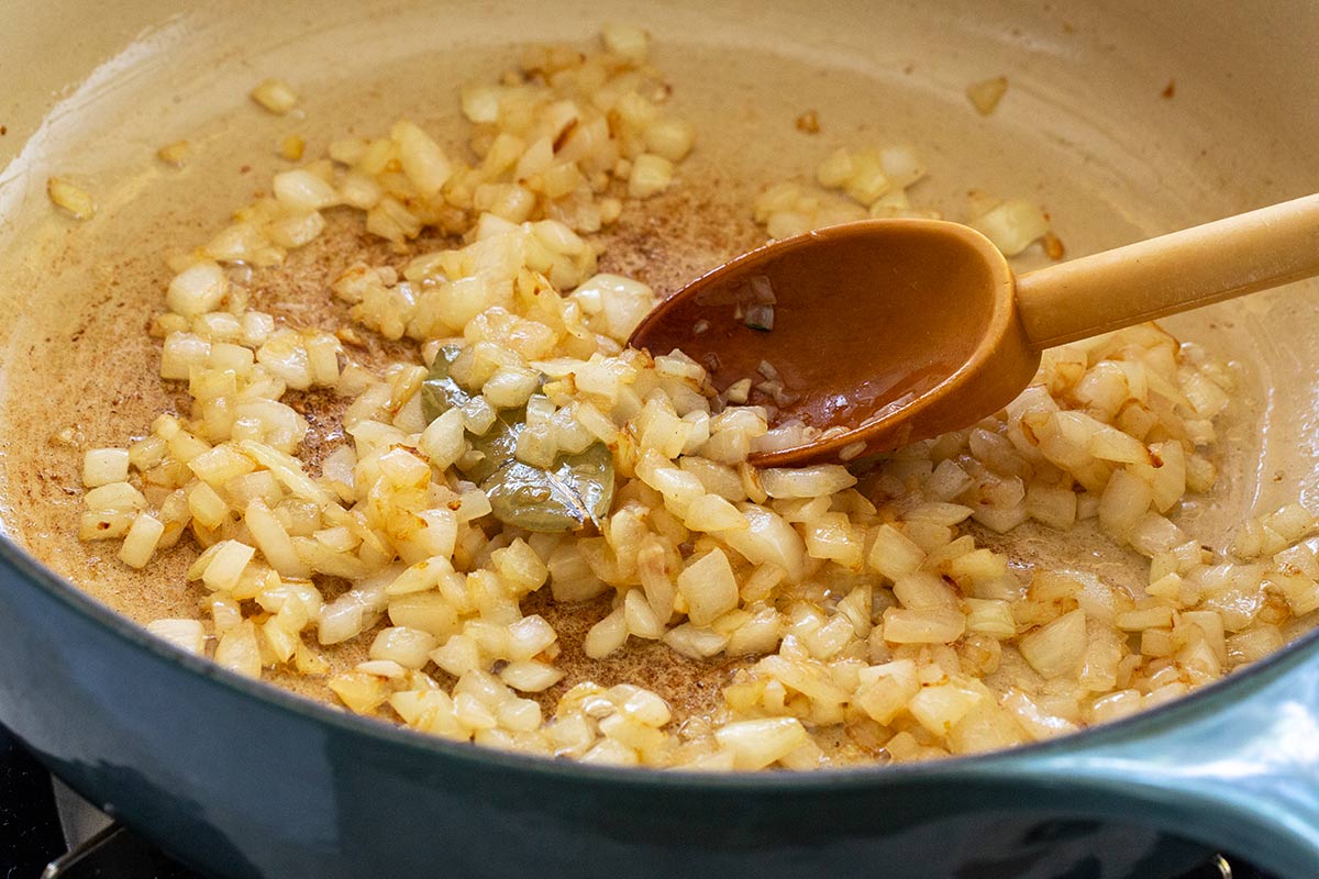 Garlic and onions in a large pot being sauteed in butter.