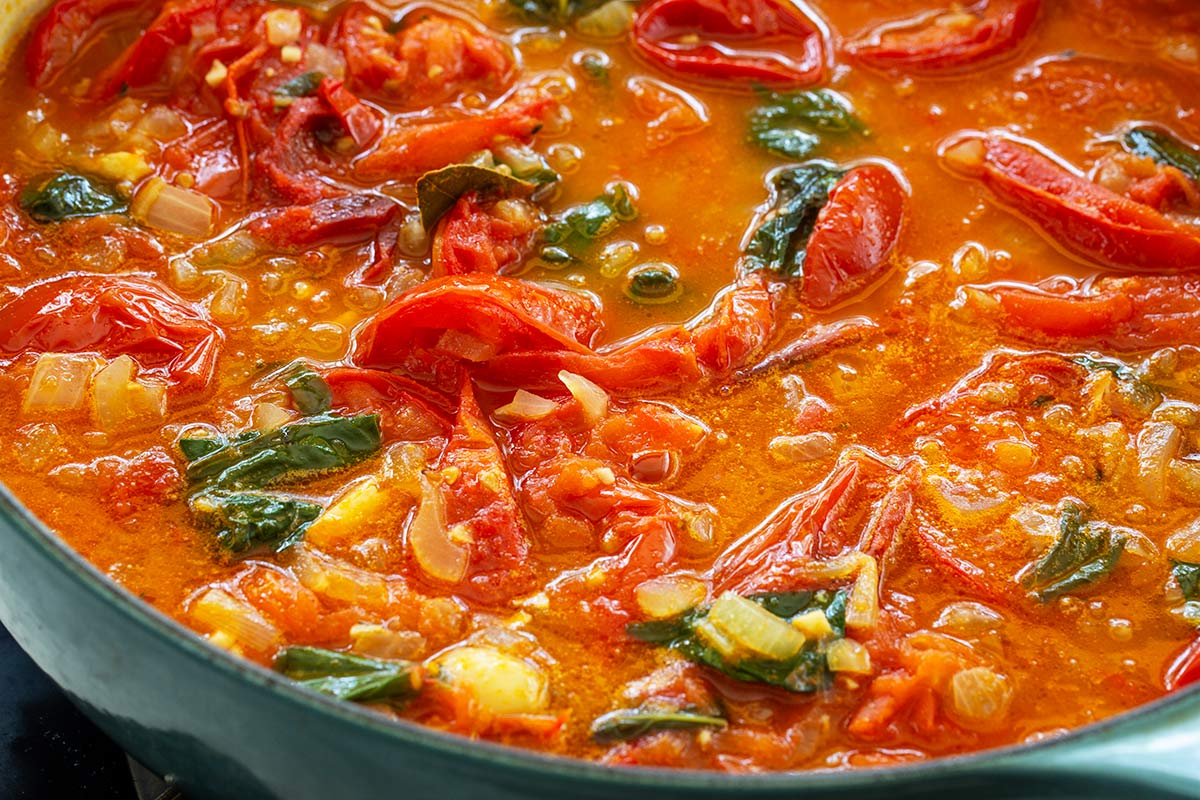 Tomato basil soup ingredients simmering in a large pot.