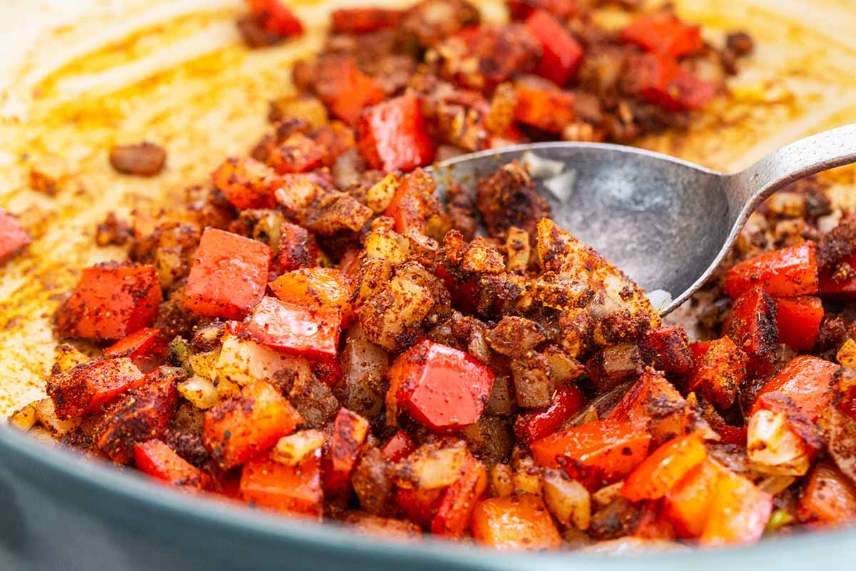 Dried seasonings placed in a dutch oven with diced tomatoes and onions.