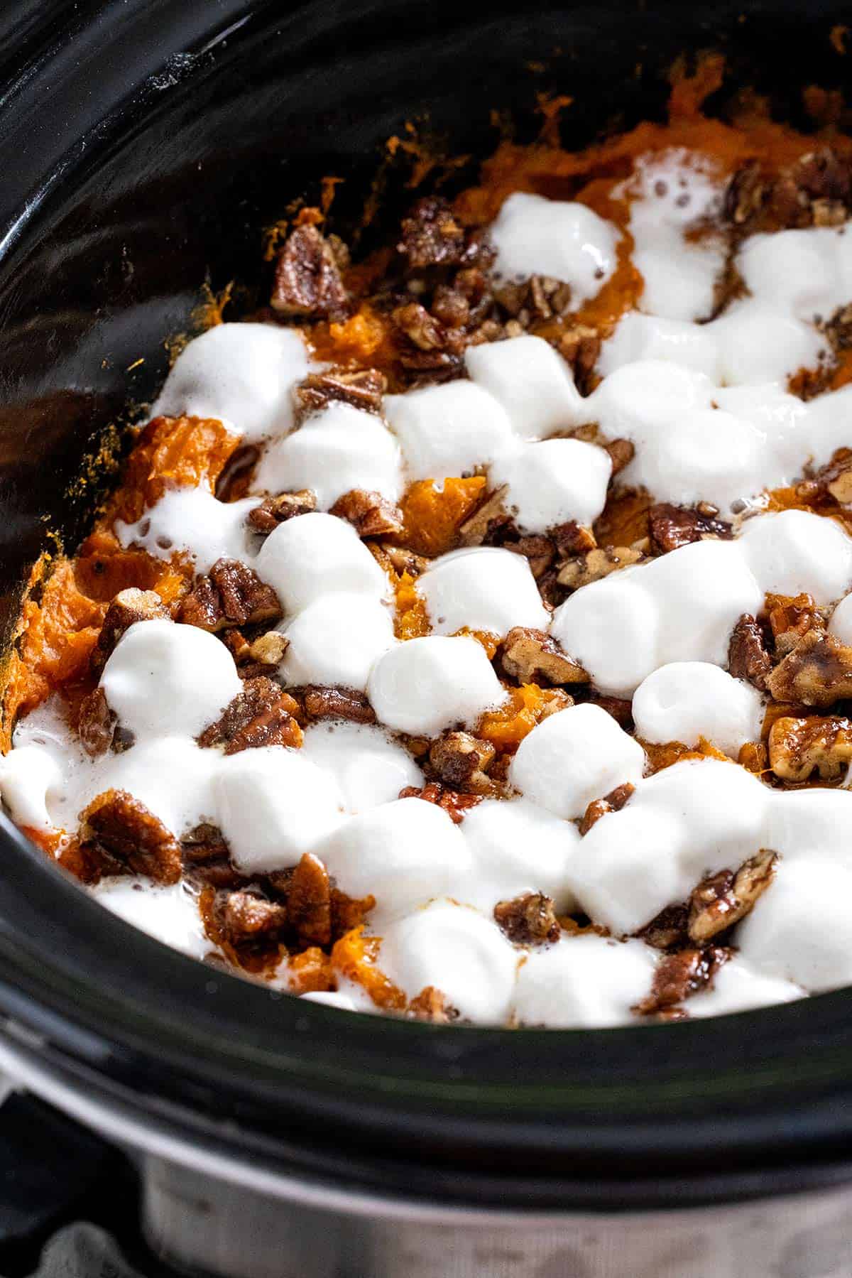 Melted mini marshmallows on top of a crockpot sweet potato casserole.