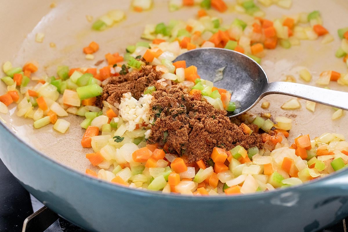 Mirepoix, a combination of onions, carrots, celery, and spices cooking in a pan.