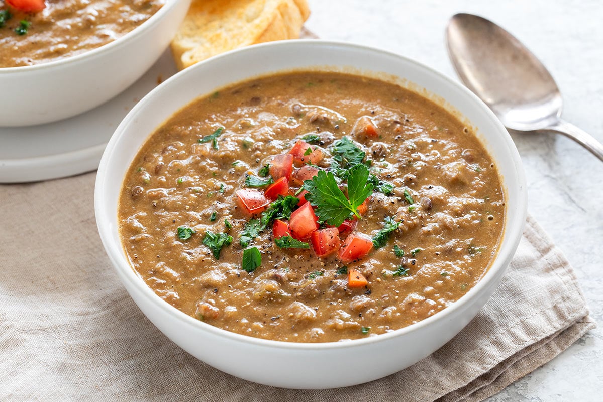 Two bowls of lentil soup served with crunchy slices of bread.