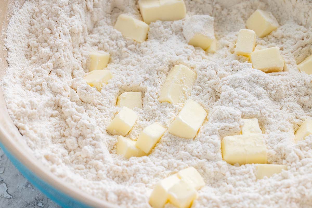 Bowl of flour mixture with cubes of butter spread throughout.