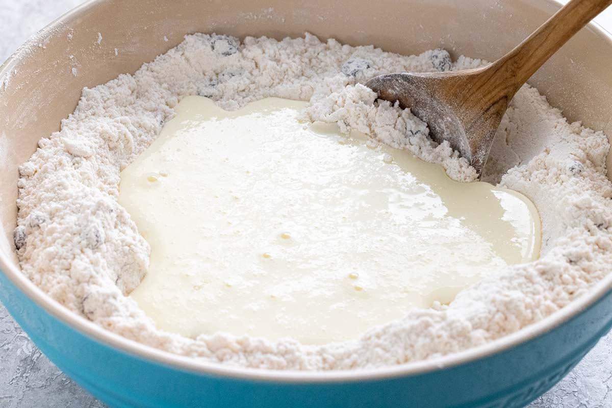 Bowl of wet and dry ingredients being mixed together to make a dough.