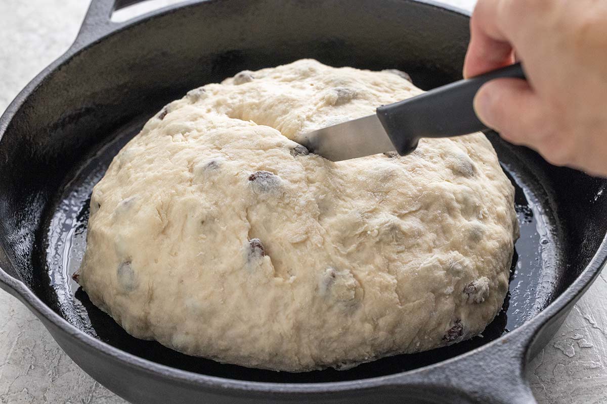 Knife slicing an X into the top of a ball of Irish soda bread dough.