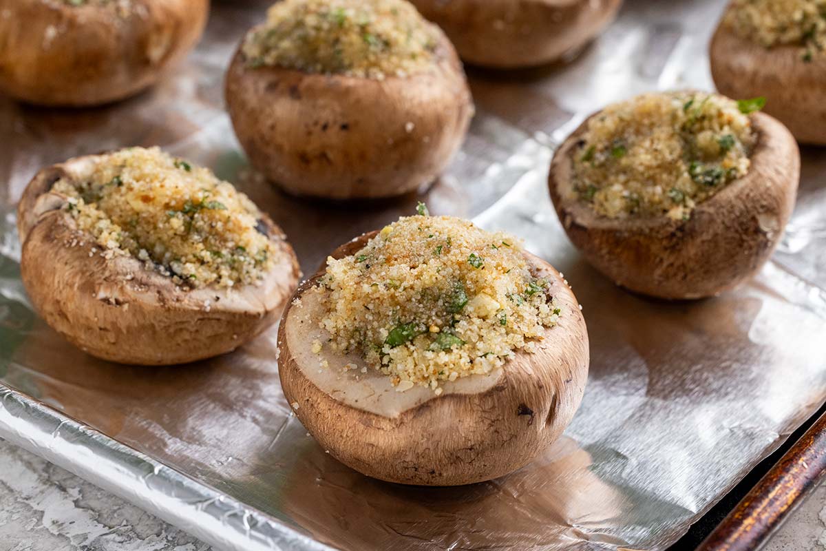 Stuffed mushrooms on a foil-lined sheet pan before baking.