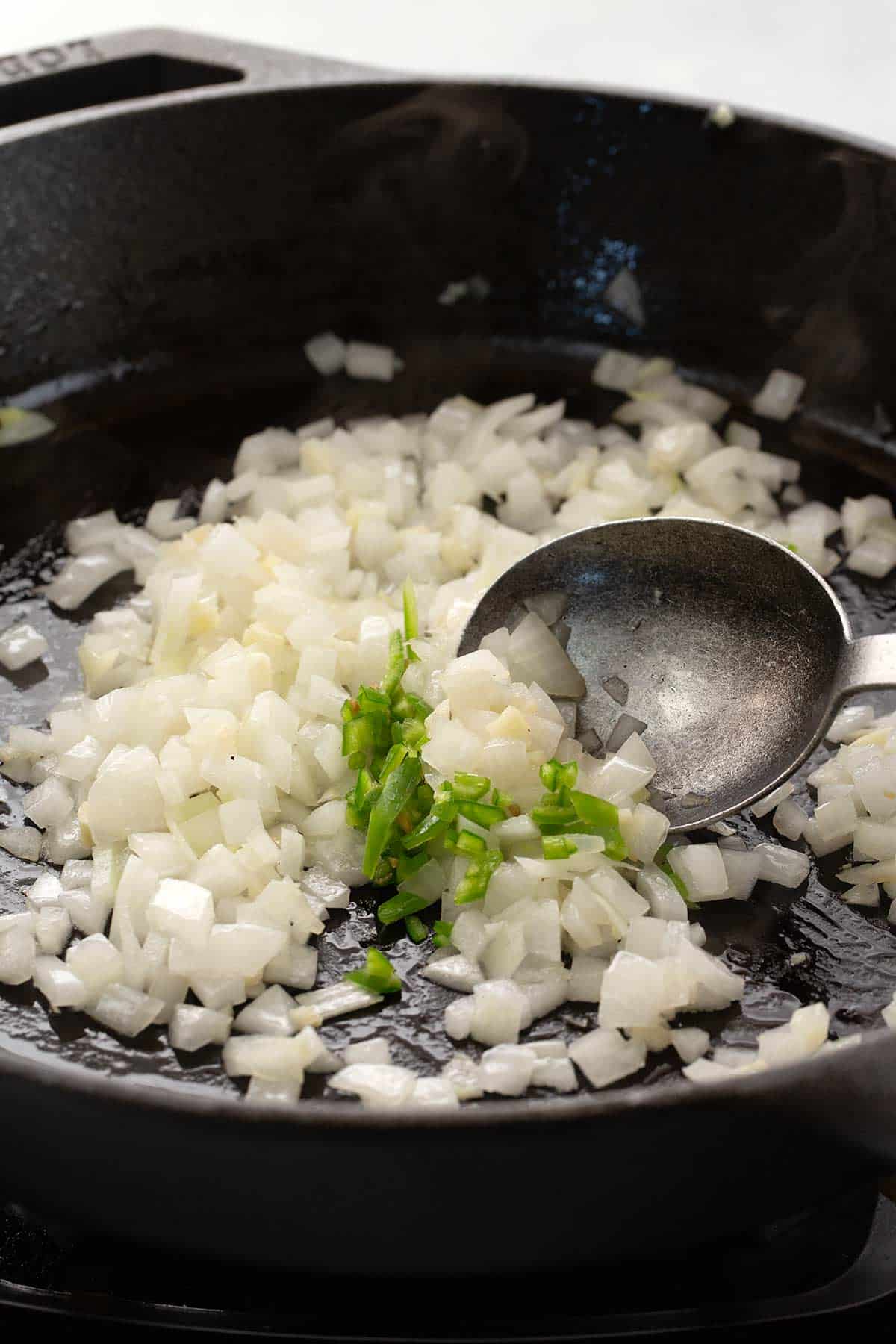 Sauteing diced onions and serrano peppers in a cast iron skillet.