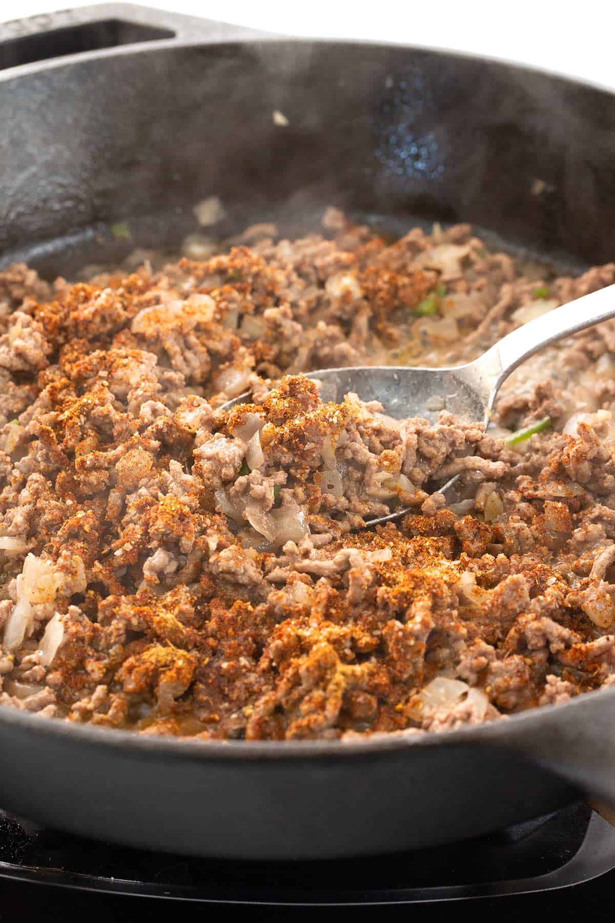 Ground beef and seasonings cooking in a pan.