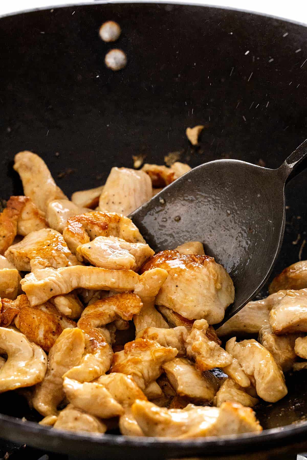 Pieces of chicken breasts cooking inside a wok.