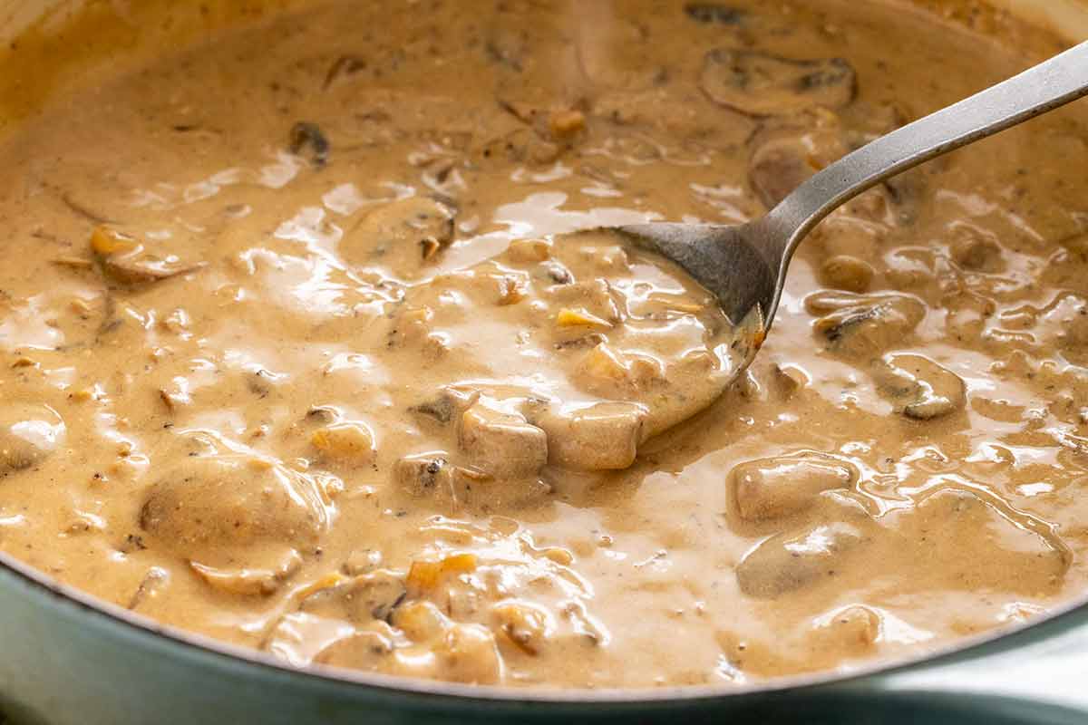 Creamy mushroom sauce being made in a pan to serve with chicken stroganoff.