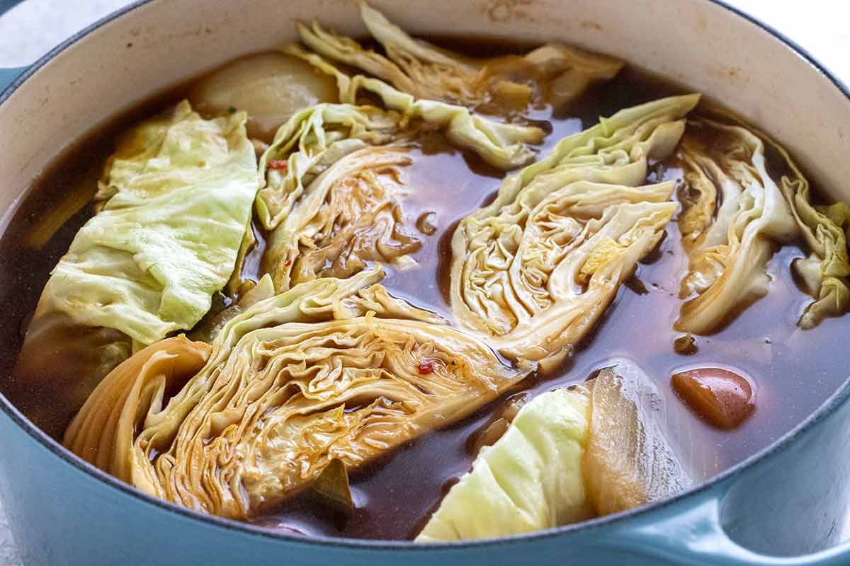 Cabbage wedges cooking in a pot of beef stock.
