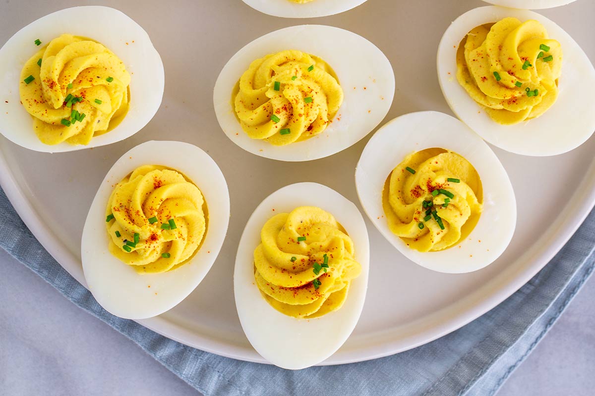 Serving platter filled with deviled eggs topped with a sprinkle of paprika and chives.