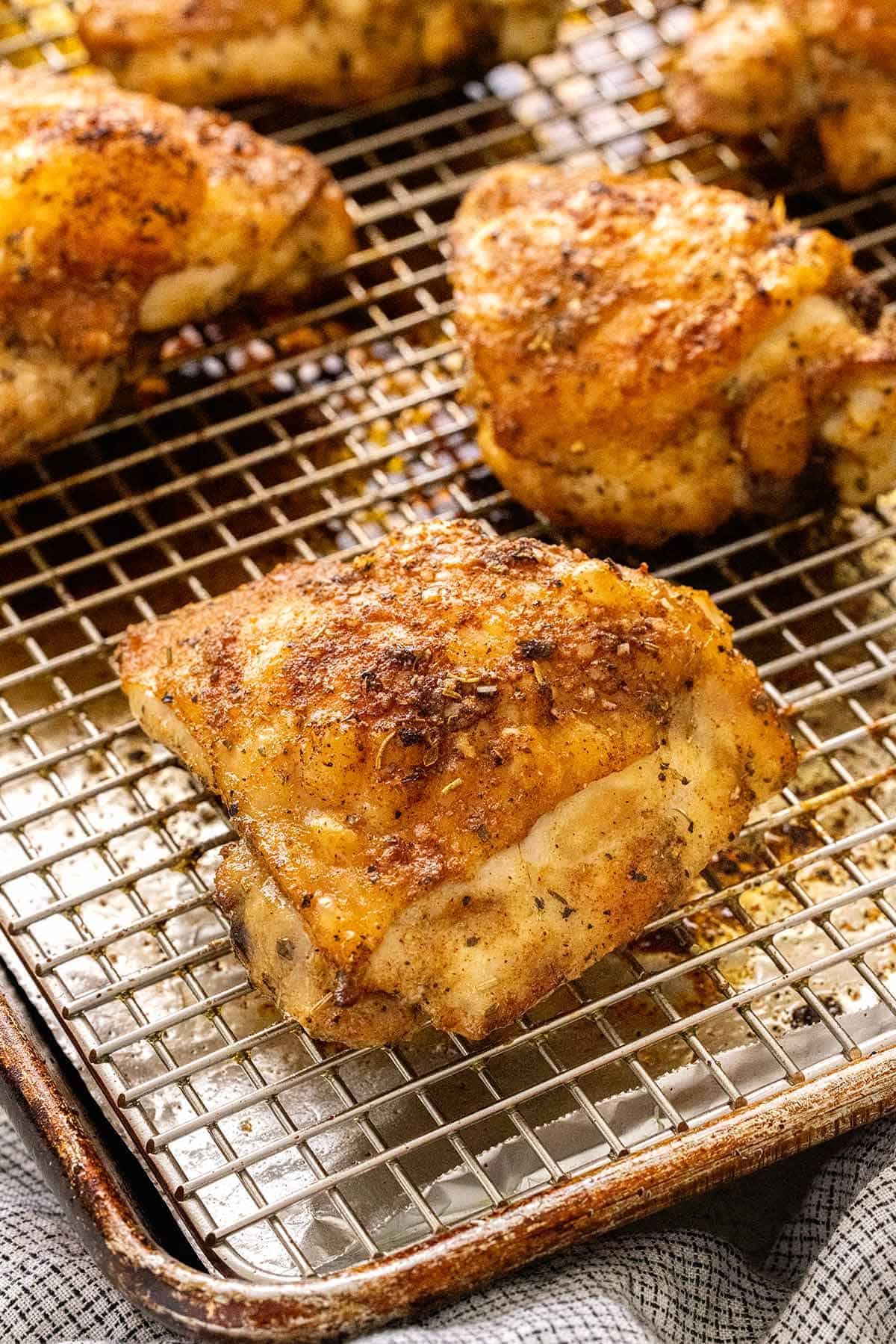 Delicious pieces of crispy baked chicken thighs cooking on a wire rack.