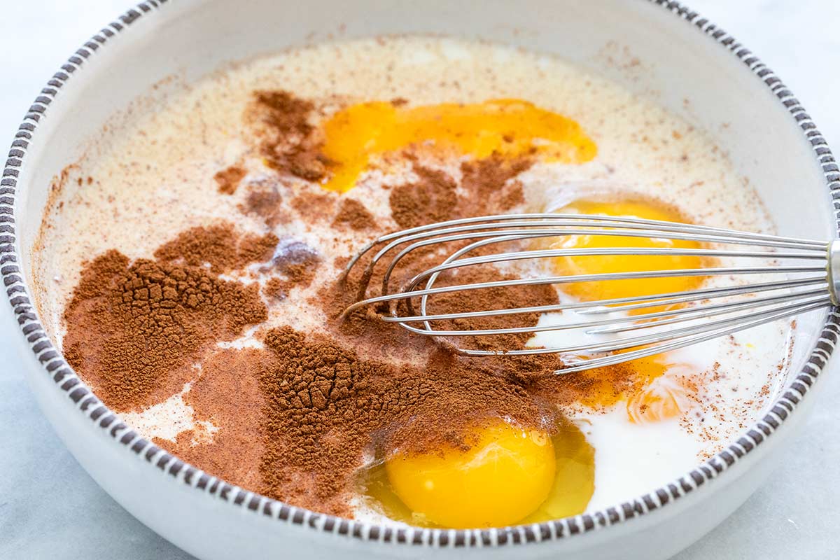 Whisk mixing egg custard in a bowl for dipping bread slices.